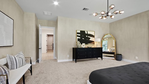 Primary bedroom with windows, white walls, and light carpet.
