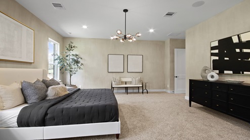Primary bedroom with windows, white walls, and light carpet.