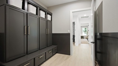 Large laundry room with a sink, light stained cabinets, white and gray quartz countertops, upgraded washer and dryer, white walls, and light vinyl wood flooring.