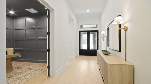 Entry hallway with brick, double doors, white walls, and light vinyl wood flooring.