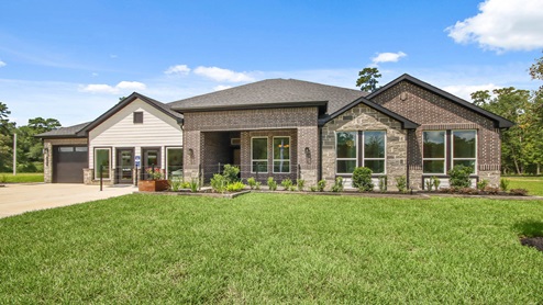 Front of the home with two tone brick, a three-car garage, and double doors.