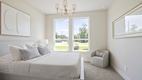 Secondary bedroom with windows, white walls, and light carpet.