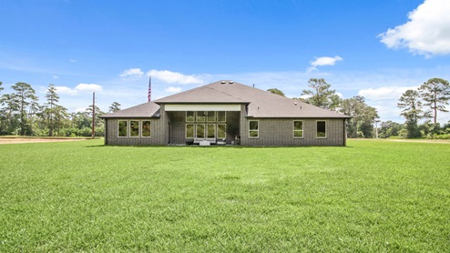 Brick back porch with a landscaped backyard.