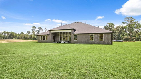 Brick back porch with a landscaped backyard.