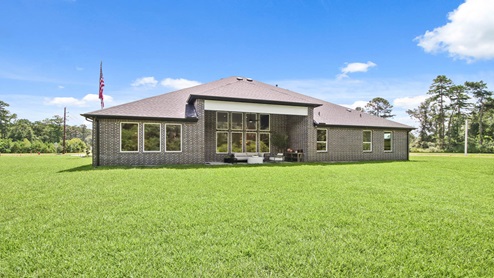 Brick back porch with a landscaped backyard.