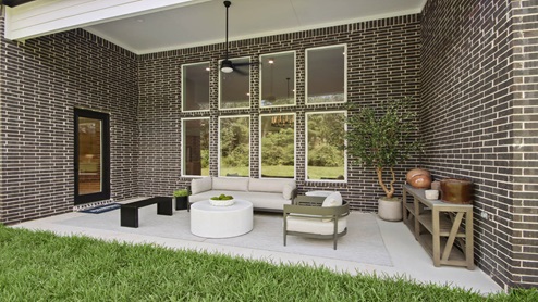 Brick back porch with a landscaped backyard.