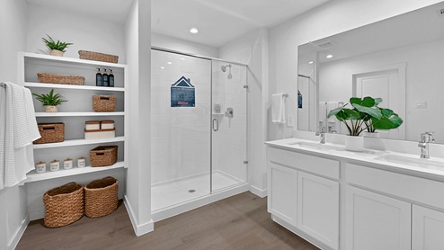 primary bathroom with standing shower and storage shelves and white cabinets
