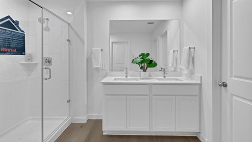 oversized primary bathroom with dual sinks with white cabinets and standing shower