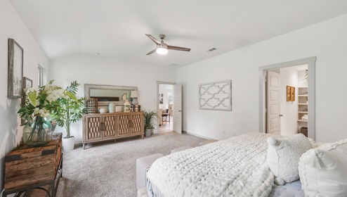 Holly Trails model home primary bedroom with a king bed and view of the primary bathroom.