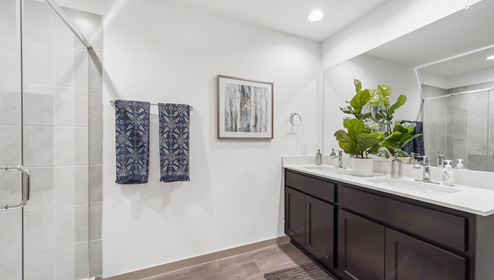 Holly Trails model home primary bathroom with double vanity sinks and mirror.