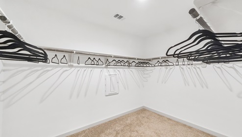 Holly Trails model home primary closet with spacious room and carpet flooring.