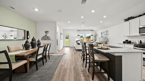 China Grove model home open concept kitchen and dining with green accent wall and decor.