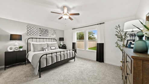 China Grove model home primary bedroom with carpet flooring and windows to backyard.