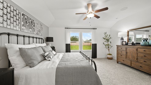 China Grove model home primary bedroom with carpet flooring and windows to backyard.