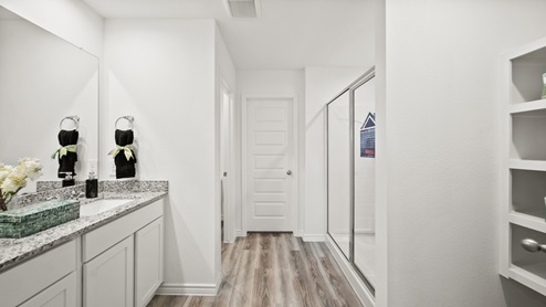 China Grove model home primary bath with white cabinets and granite countertops and walk-in shower.