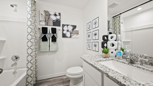 China Grove model home secondary bath with white cabinets and granite countertops.