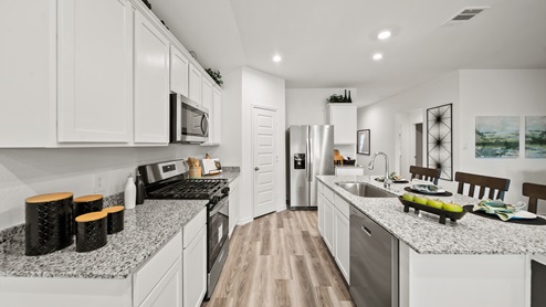 China Grove model home kitchen with vinyl plank flooring, white cabinets and granite countertops.