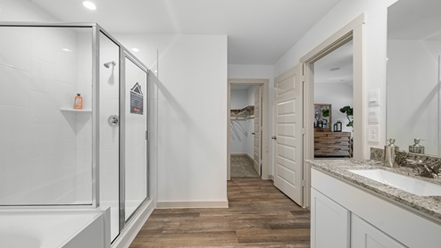 Windemere model home primary bathroom with walk-in shower and view of the walk-in closet.