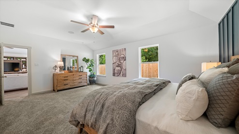 Windemere model home primary bedroom with a king bed and carpet flooring.