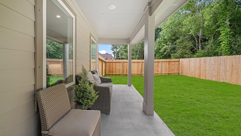 Windemere model home back patio with a view of the backyard and brown wooden plank fence.