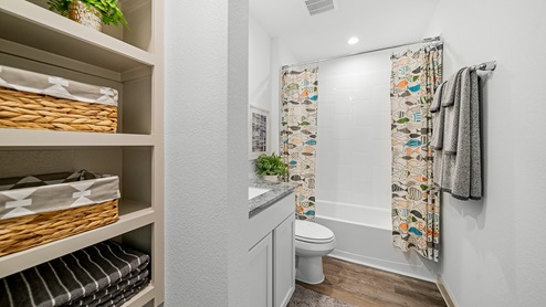 Windemere model home secondary bathroom with storage shelving and a bathtub and shower combo.