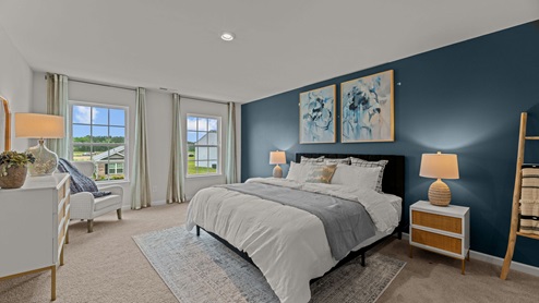 Primary bedroom with blue accent wall and carpet flooring