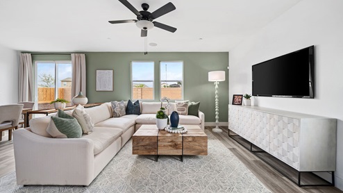 Photo of an open concept living room with large windows, a sectional couch, and decor