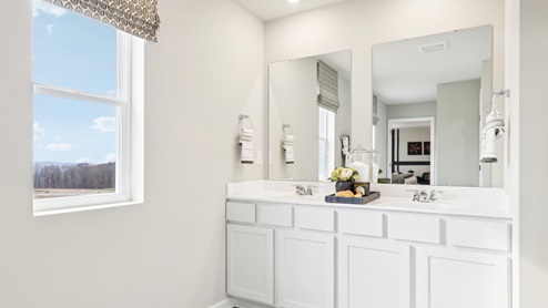 primary en suite bathroom with windows and dual vanity