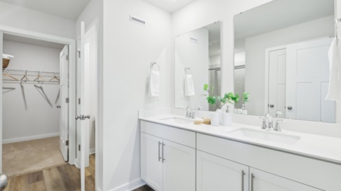 Primary ensuite full bath with dual vanity and glass shower door
