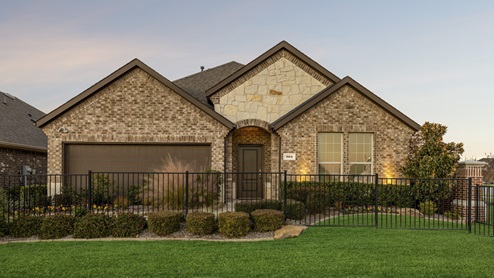 Secondary model with exterior lighting and lush green landscaping
