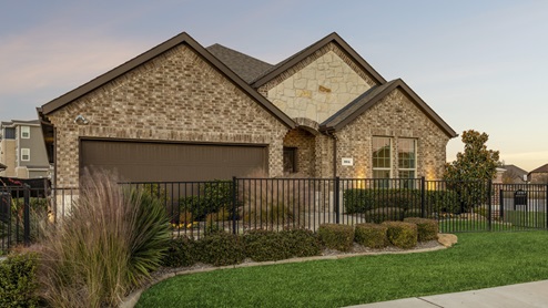 Secondary model with exterior lighting and lush green landscaping