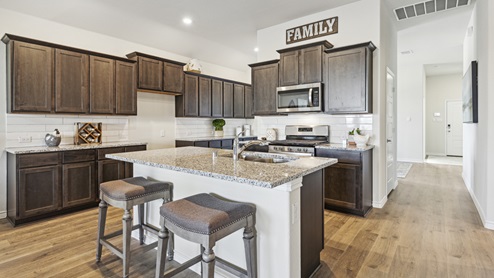 Kitchen with island and brown cabinets and elongated countertops