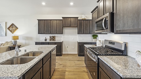 Kitchen with island and brown cabinets and elongated countertops
