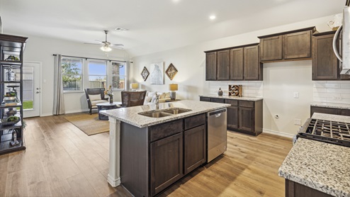 Kitchen with island and brown cabinets and elongated countertops