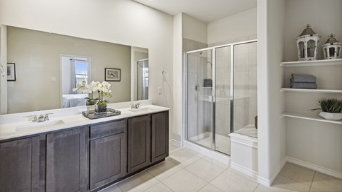 Primary bathroom with long vanity with brown cabinets and a walk-in shower and shelving