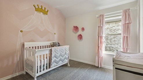 Bedroom decorated as a pink nursery with crib and changing table