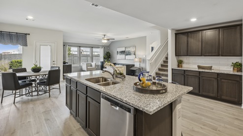 Large open concept kitchen with island and views into living room with windows