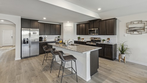 Large kitchen island with brown cabinets and large granite countertops