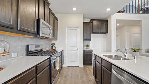 elongated kitchen countertops with brown cabinets and stainless steel appliances