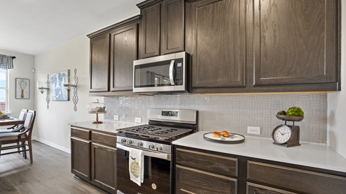 elongated kitchen countertops with brown cabinets and stainless steel appliances