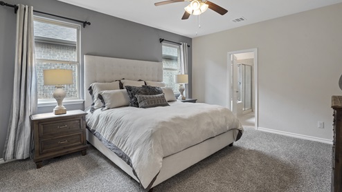 large primary bedroom with large bed and two windows
