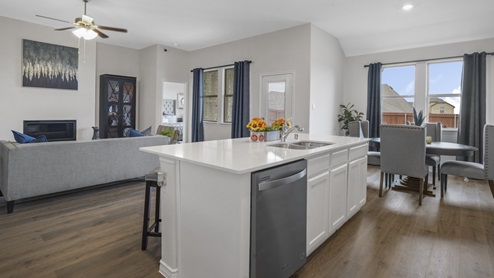 kitchen with white counters and cabinets overlooking living room and breakfast nook with window