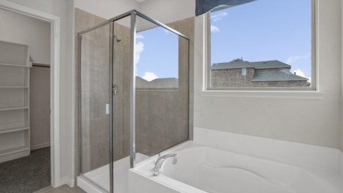 large primary bathroom with shower and large garden tub next to window