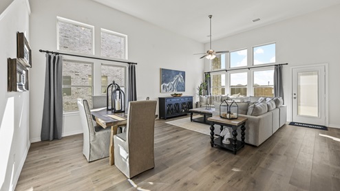 large living area with several windows and wood plank flooring