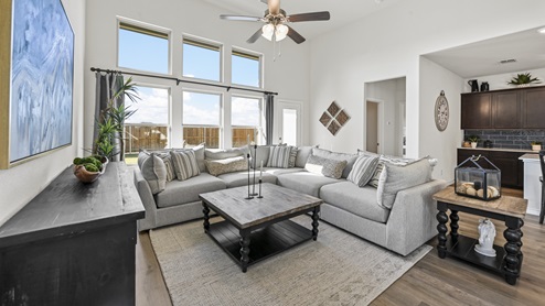 large living area with several windows and wood plank flooring and ceiling fan