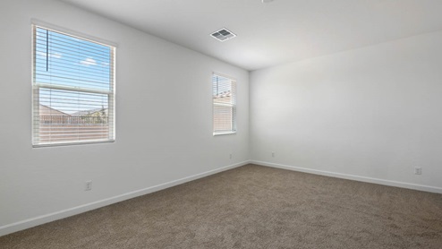 A spacious primary bedroom emphasizing open space and natural lighting.