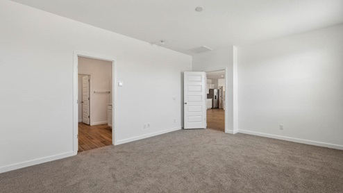 A spacious primary bedroom emphasizing open space and natural lighting.