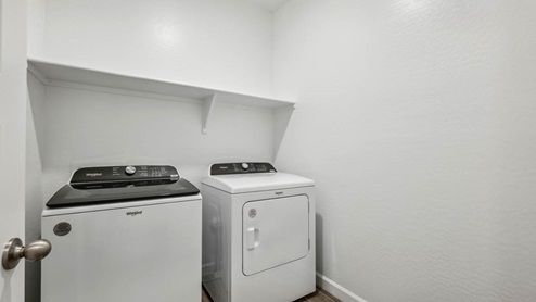 A laundry room featuring a washer and dryer, neatly arranged with ample space for laundry tasks and storage.