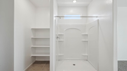 Modern primary bathroom with double vanities, granite countertops with a walk-in shower and a walk-in closet.