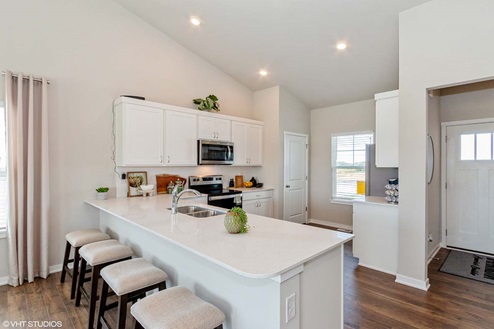 spacious kitchen with white cabinetry and small window